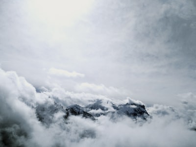 白天多云的天空下，山被雪覆盖